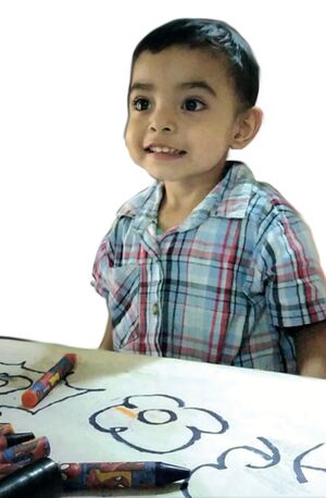 Niño preescolar pinta con crayones en cartulina.