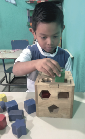 Niño preescolar juega con figuras geométricas.