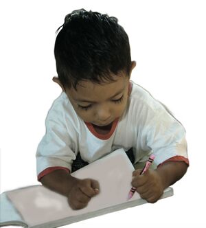 Niño preescolar escribe en cuaderno.
